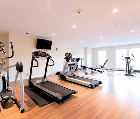 A home gym with treadmills, elliptical machines, and other exercise equipment.