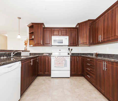 A kitchen with brown cabinets and white appliances.