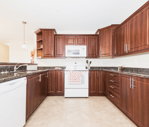 A kitchen with brown cabinets and a white dishwasher.