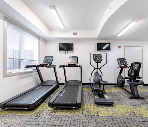A gym with treadmills, exercise bikes, and a television.