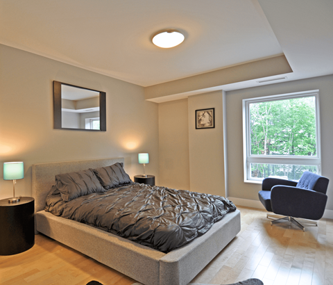 A bedroom with a large bed and a chair.