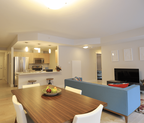 A modern dining room with a wooden table and white chairs.