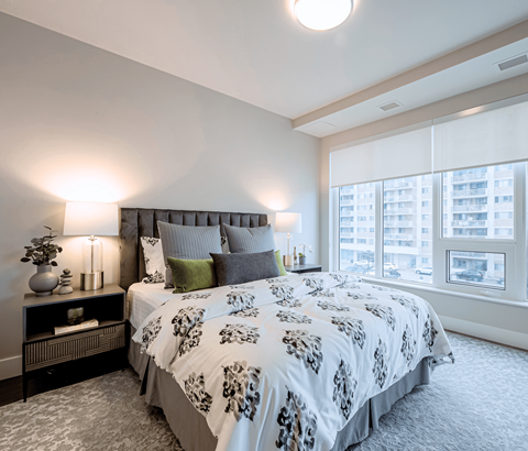 A bedroom with a large bed and a window overlooking a cityscape.