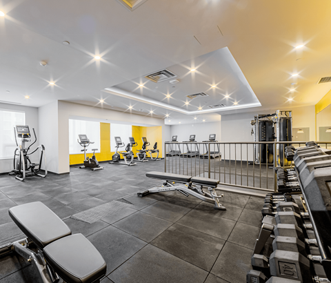 A well-lit gym with various exercise equipment.