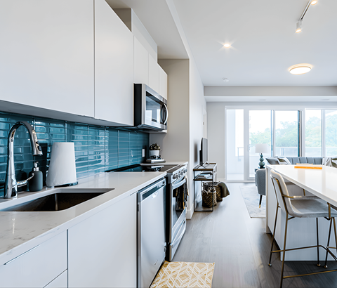 A modern kitchen with white cabinets and a blue tile backsplash.