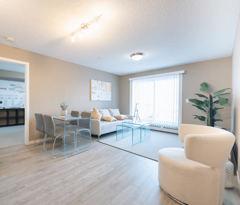 A modern living room with a glass table and white chairs.