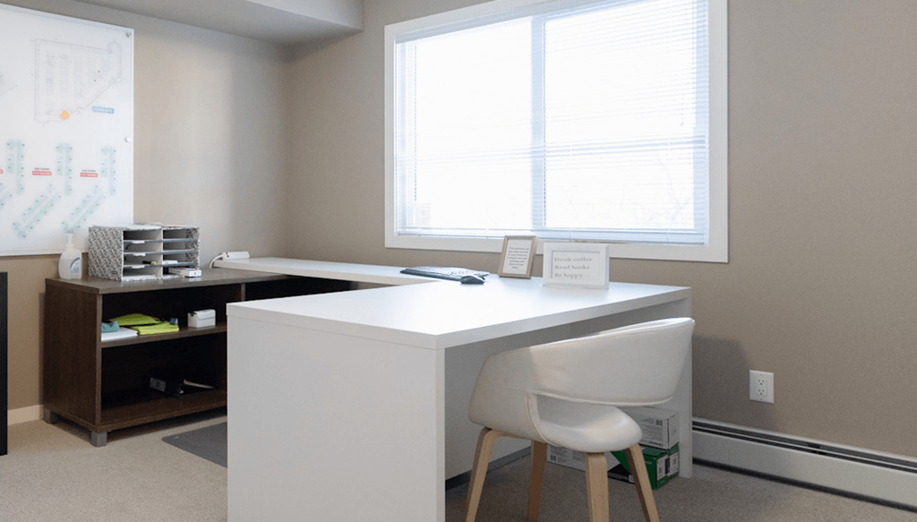 an office with a desk and a chair in front of a window