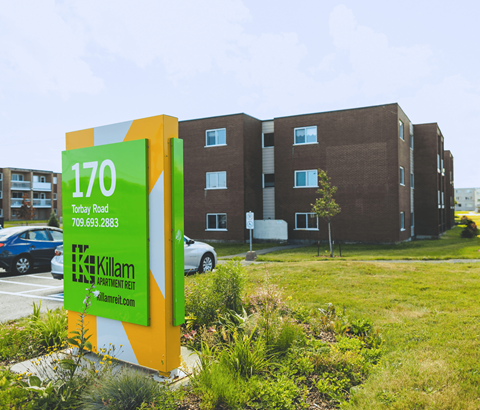 A sign for Killam Apartment Rent in front of a building.