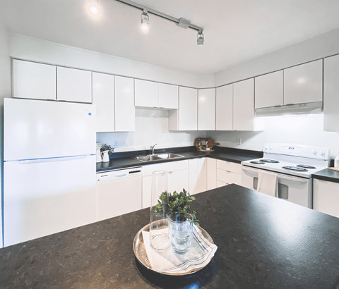 A kitchen with white cabinets and a black countertop.