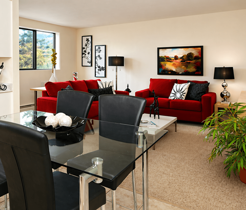 A modern living room with a glass dining table and red couch.