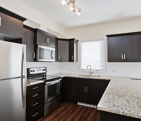 A kitchen with black cabinets and a granite countertop.