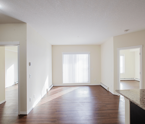 A large empty room with wooden floors and white walls.