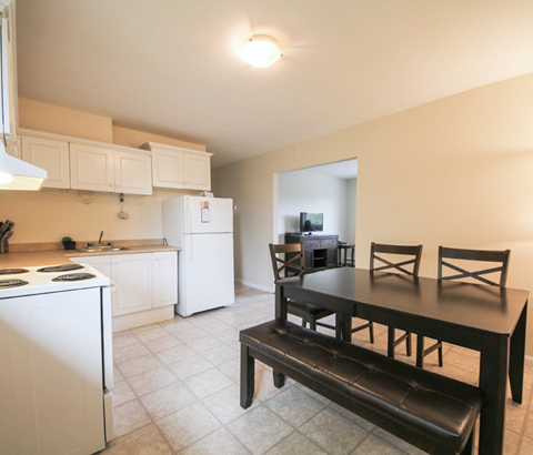 A kitchen with a white refrigerator and a black table.
