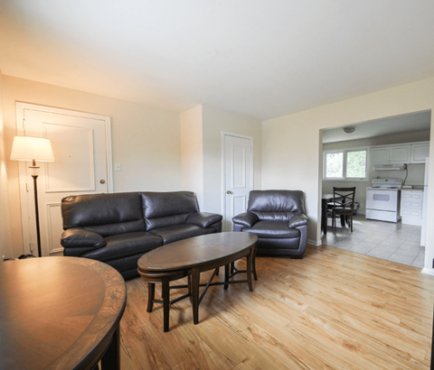A living room with a black leather couch and a wooden table.