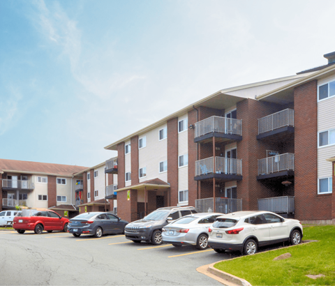 A parking lot with cars and apartment buildings.
