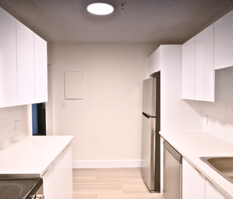 A kitchen with white cabinets and a stainless steel refrigerator.