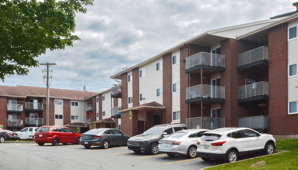 A parking lot with cars and apartment buildings.