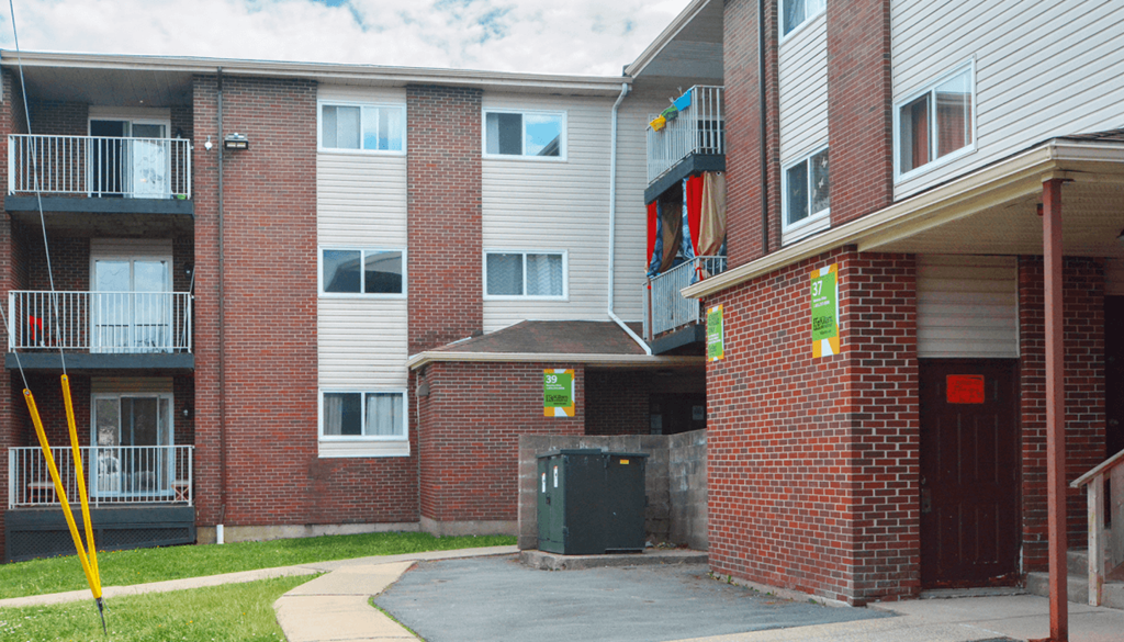 Apartment building with a red door and a green trash can.