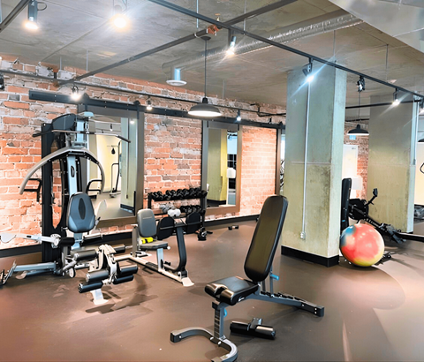 A gym with a variety of equipment including a weight bench, a leg press machine, and a medicine ball.