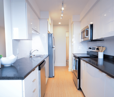 A modern kitchen with white cabinets and black countertops.