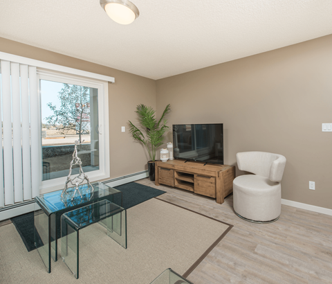 A living room with a glass coffee table and a white chair.