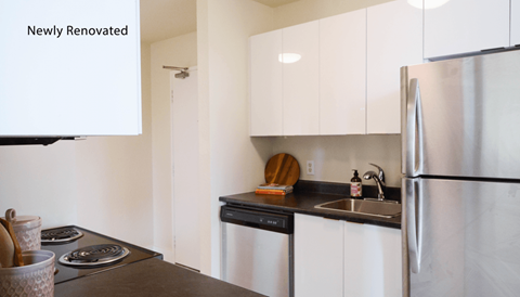 A kitchen with white cabinets and a stainless steel refrigerator.