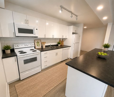 A modern kitchen with white cabinets and black countertops.