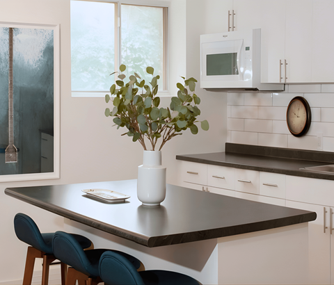 A kitchen with a table, chairs, and a vase of flowers.