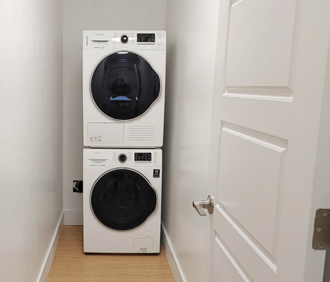 A white front loading washing machine in a small room.