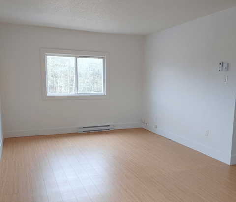 A room with a window and wooden flooring.