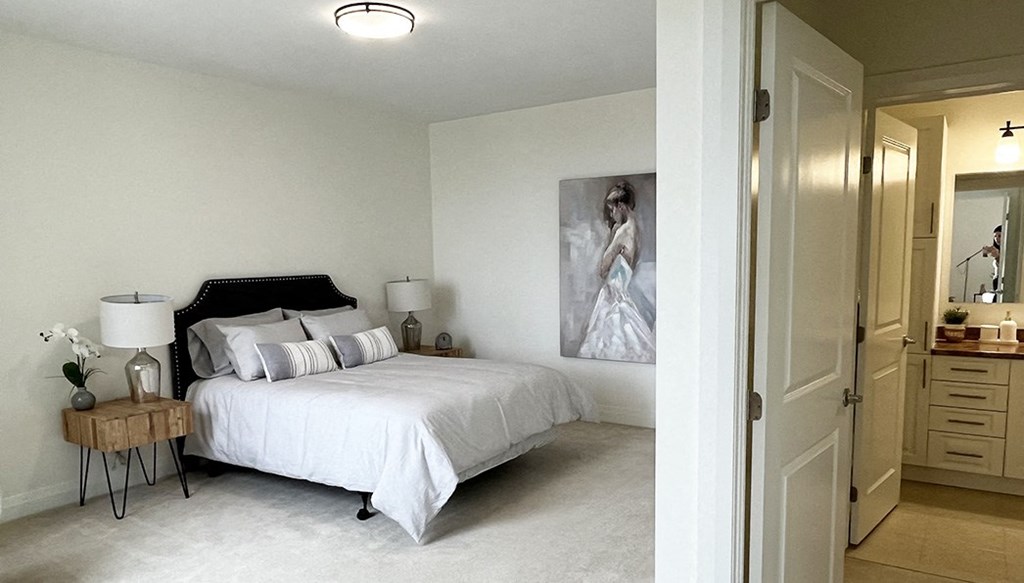 a bedroom with a white bed and a painting on the wall