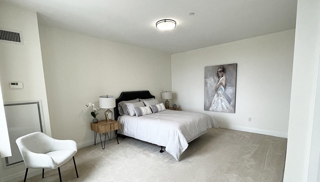 a white bedroom with a bed and a white chair