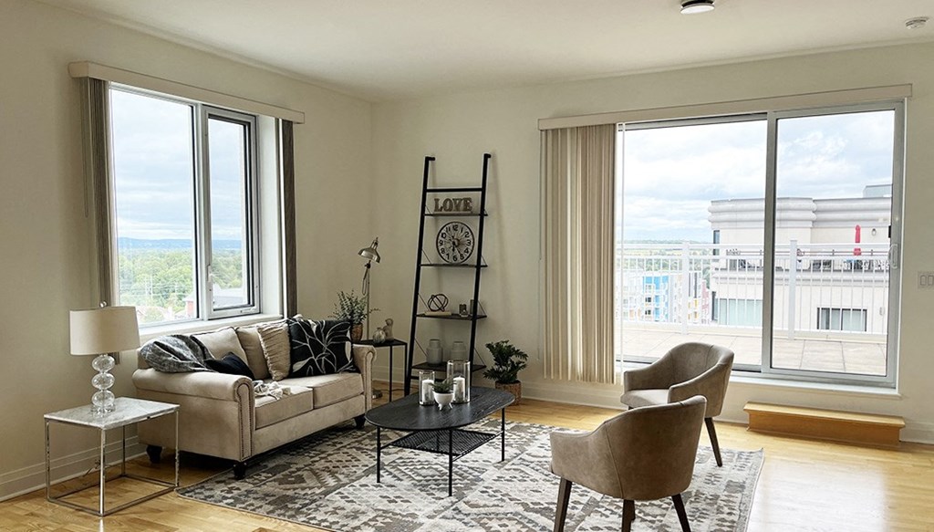 a living room with a couch and chairs and large windows