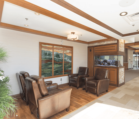 A living room with brown leather chairs and a large window.