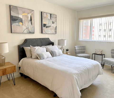 A bedroom with a large bed and two abstract paintings on the wall.