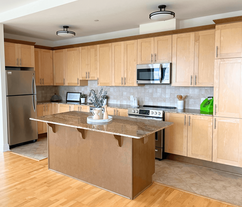 A kitchen with wooden cabinets and a stainless steel refrigerator.