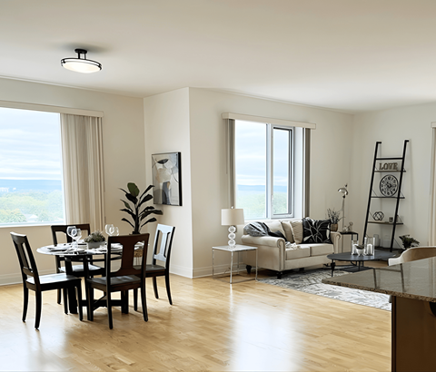 A dining room with a table set for two and a couch with a decorative pillow.