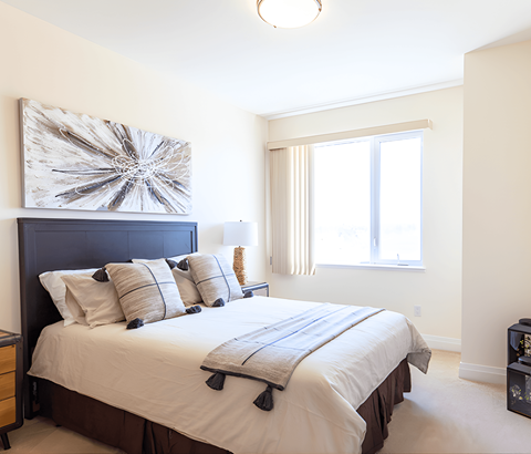 A bedroom with a large bed and a large abstract painting above it.