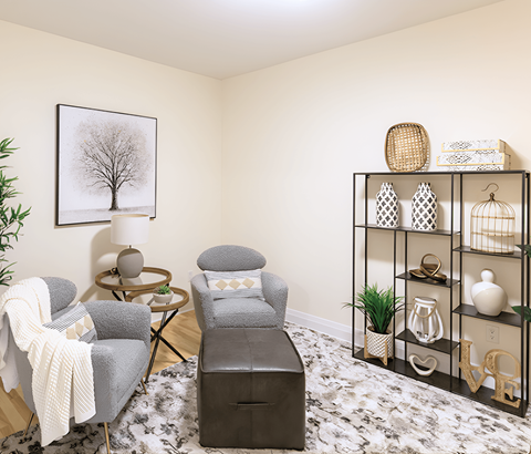 A living room with a grey chair and a black ottoman.