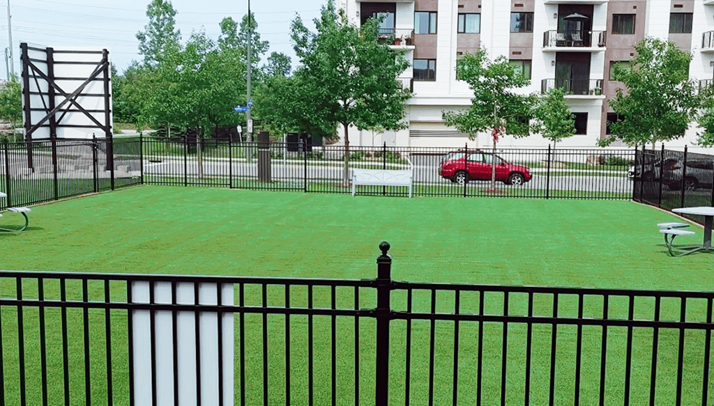 a yard with a red car parked in front of an apartment building