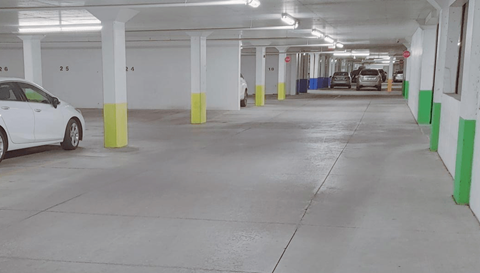 a parking garage with cars and green and yellow pillars