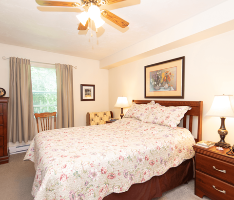 A bedroom with a large bed and a ceiling fan.