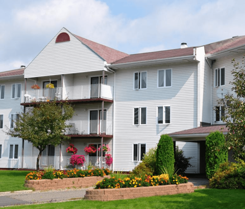 A white building with a red roof and a balcony with flowers.