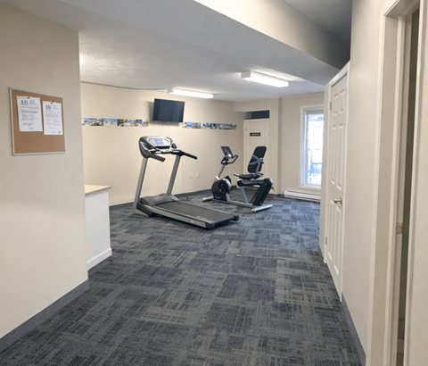 A gym room with a treadmill and a stationary bike.