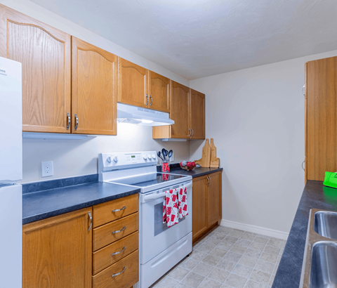 A kitchen with wooden cabinets and a white stove top oven.