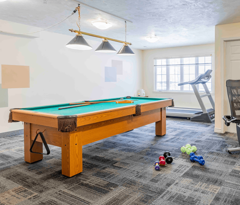 A pool table with a green felt cloth and a set of pool balls on the floor.