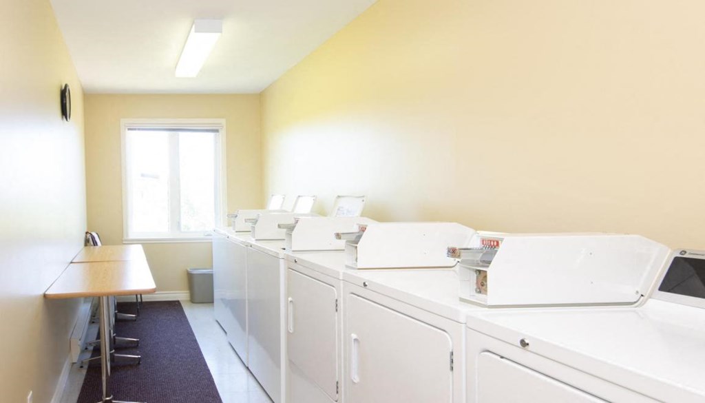 a laundry room with four washing machines and a table