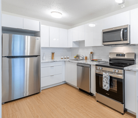 A modern kitchen with a stainless steel refrigerator, oven, and microwave.