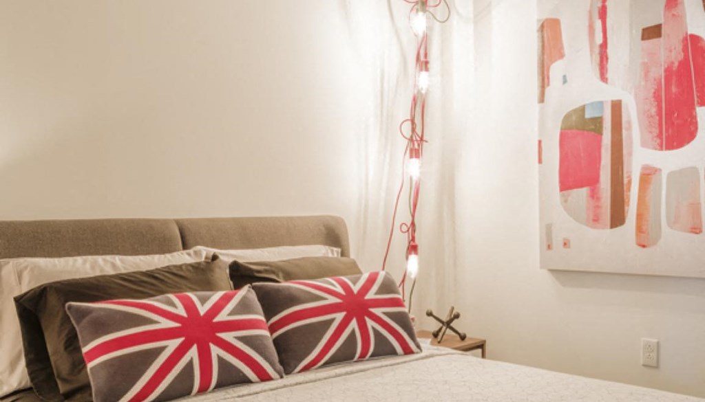 a bedroom with a bed and pillows and paintings on the wall