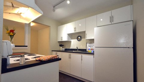 A kitchen with white cabinets and a black countertop.
